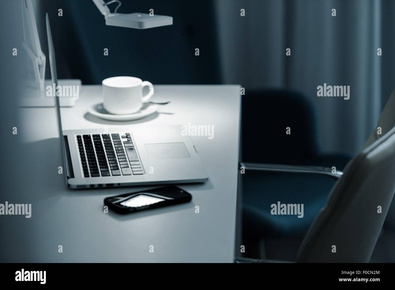 Le travail à l'ordinateur pendant la nuit. Ordinateur portable ordinateur de bureau lampe et tasse à café. Banque D'Images