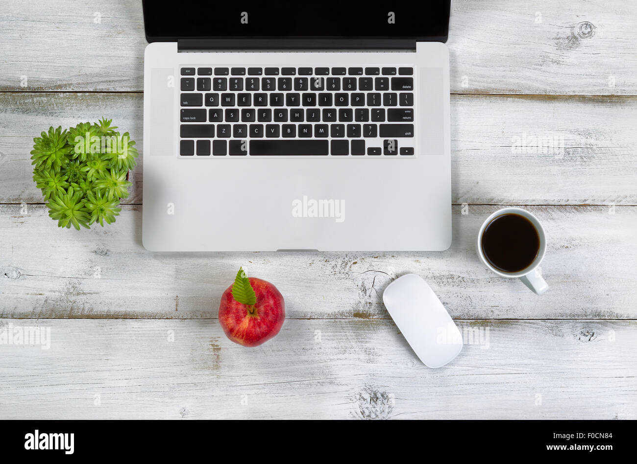 Pomme Rouge, du café, de la souris, des plantes et de l'ordinateur portable sur le dessus de bureau blanc rustique. Banque D'Images
