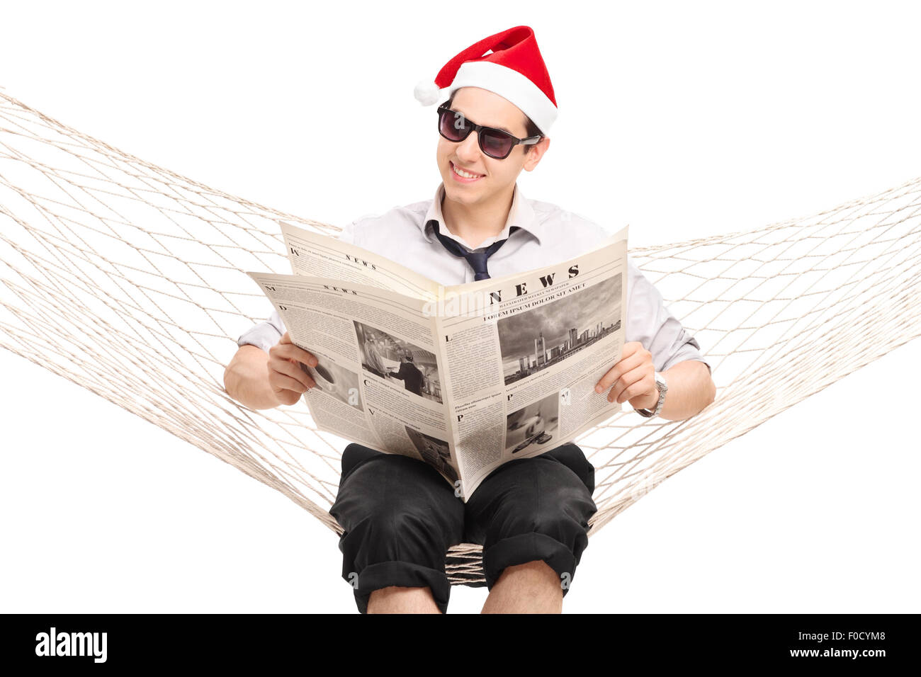 Les jeunes guy with Santa hat assis dans un hamac et lire un journal isolated on white Banque D'Images
