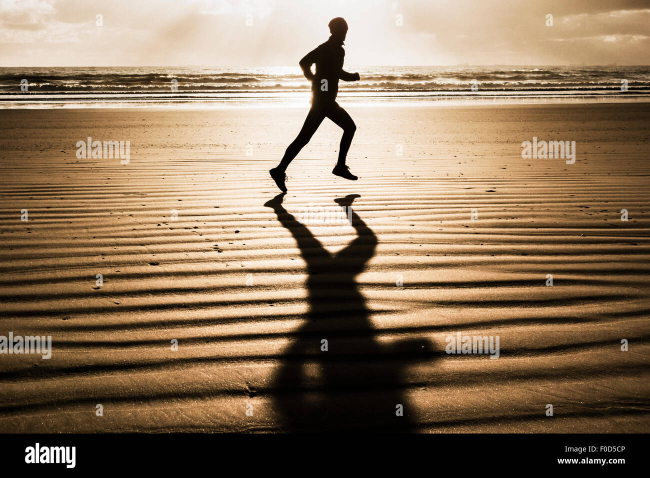 Homme qui court sur la plage au lever du soleil découpé sur rising sun Banque D'Images
