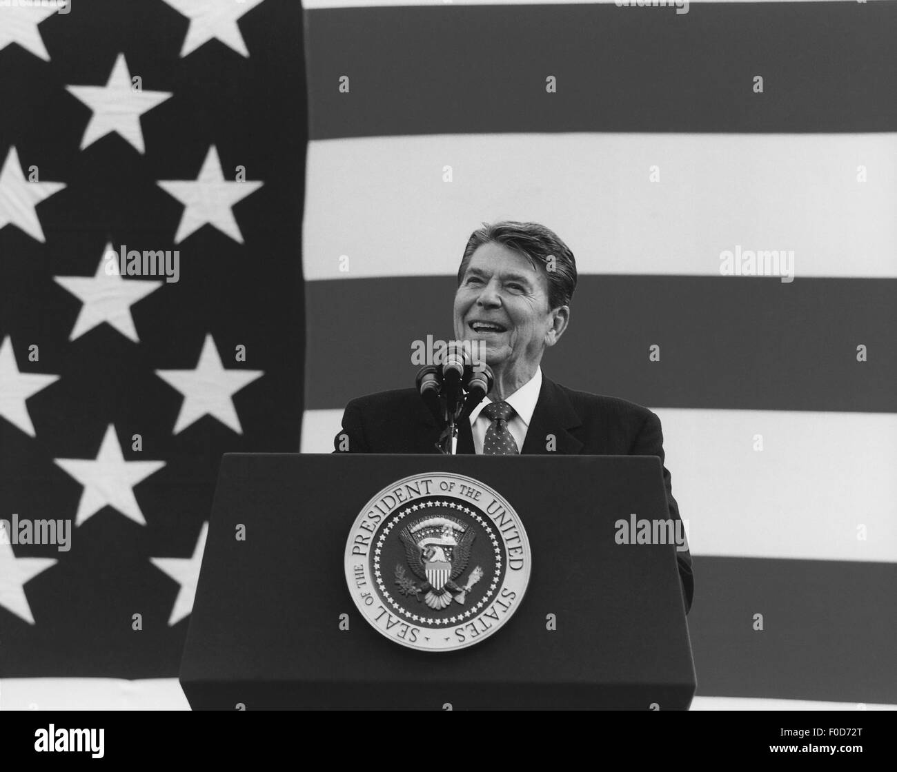 Le président Ronald Reagan s'exprimant devant un grand drapeau américain. Banque D'Images