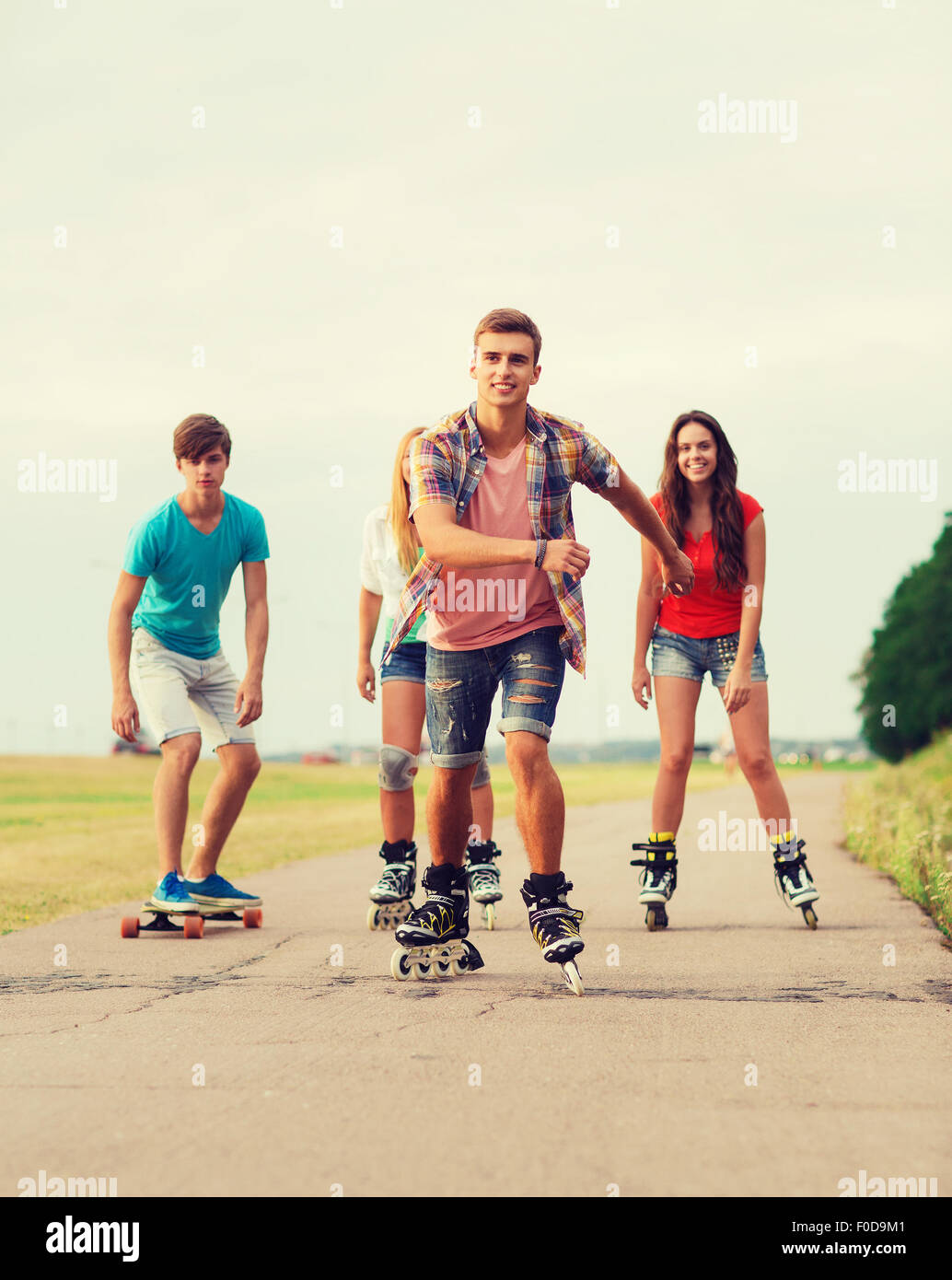 Groupe d'adolescents souriants avec patins à roulettes Banque D'Images