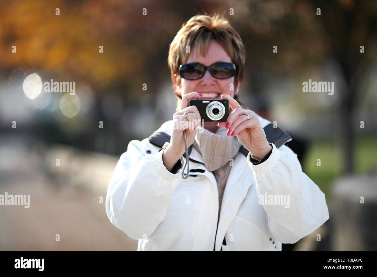 Une femme d'âge moyen, un touriste, tenant son appareil photo prendre une photo vers le photographe. Elle est à l'aide du viseur arrière pour composer la photo Banque D'Images