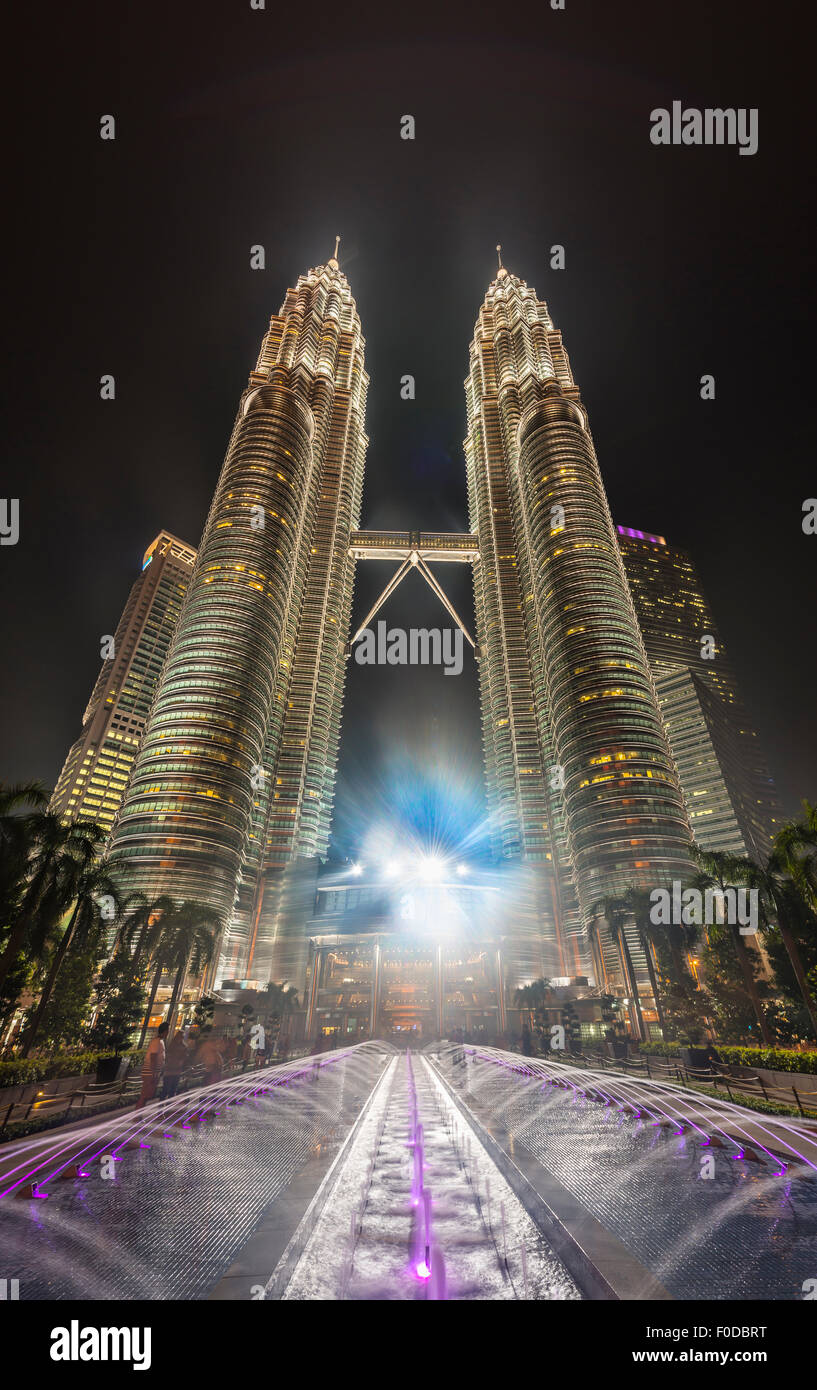 Fontaine en face de la tour Petronas illuminée la nuit, Kuala Lumpur, Malaisie Banque D'Images