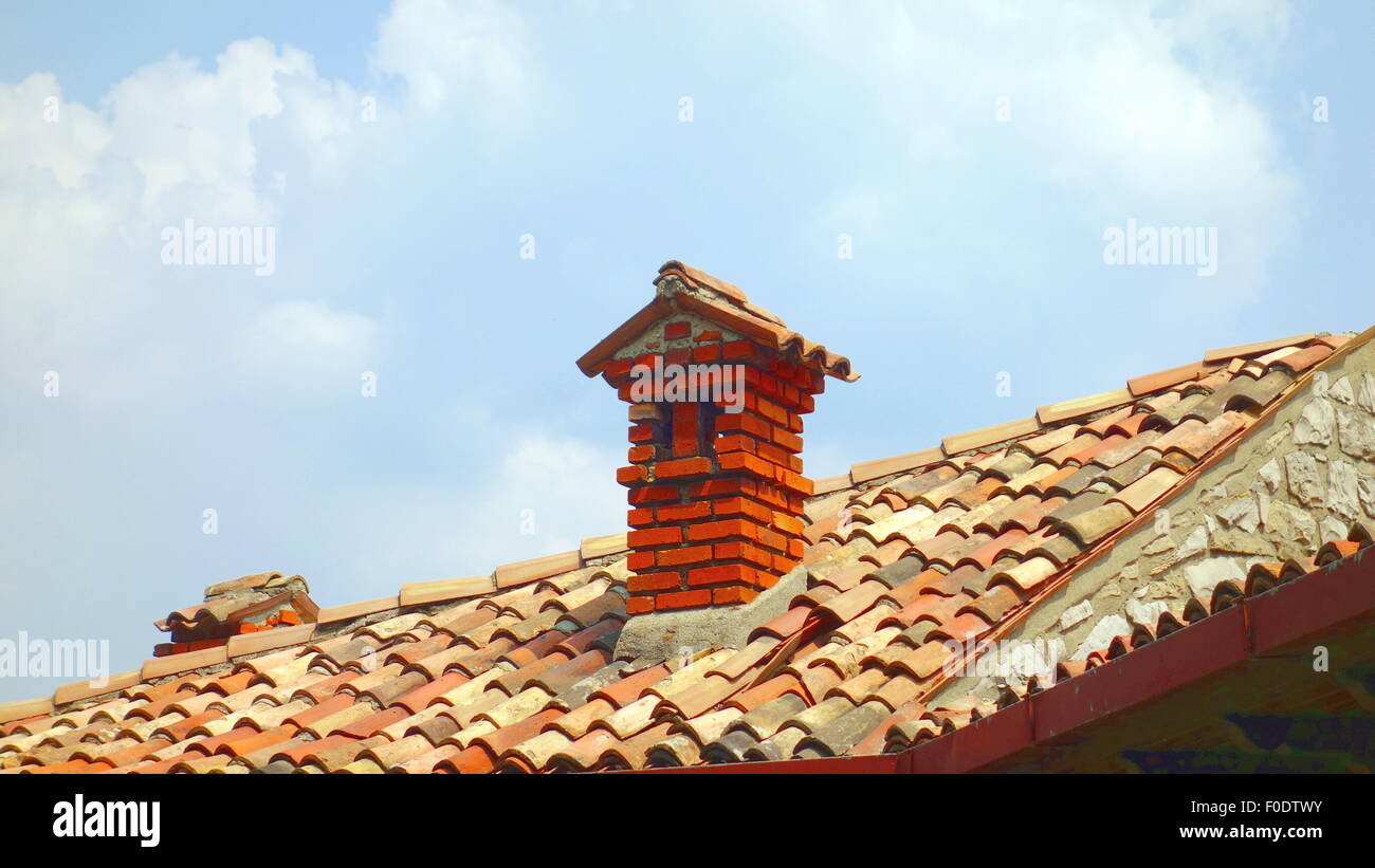 Des briques rouges cheminée sur le haut d'un toit en terre cuite Banque D'Images