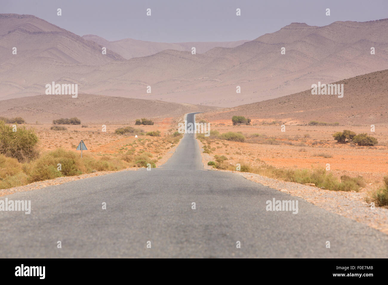 Route droite à travers le désert dans la région de Tata, montagnes en arrière-plan. Le Maroc, l'Afrique Banque D'Images