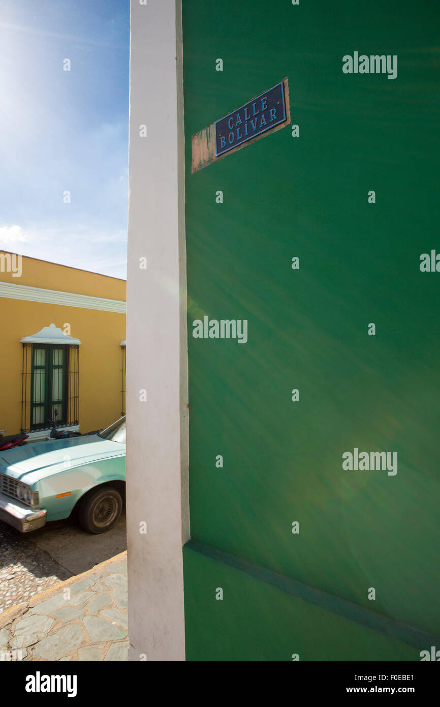 Ancien centre colonial de Ciudad Bolivar avec calle Bolivar sur un mur vert et une vieille voiture américaine dans l'arrière-plan. Banque D'Images