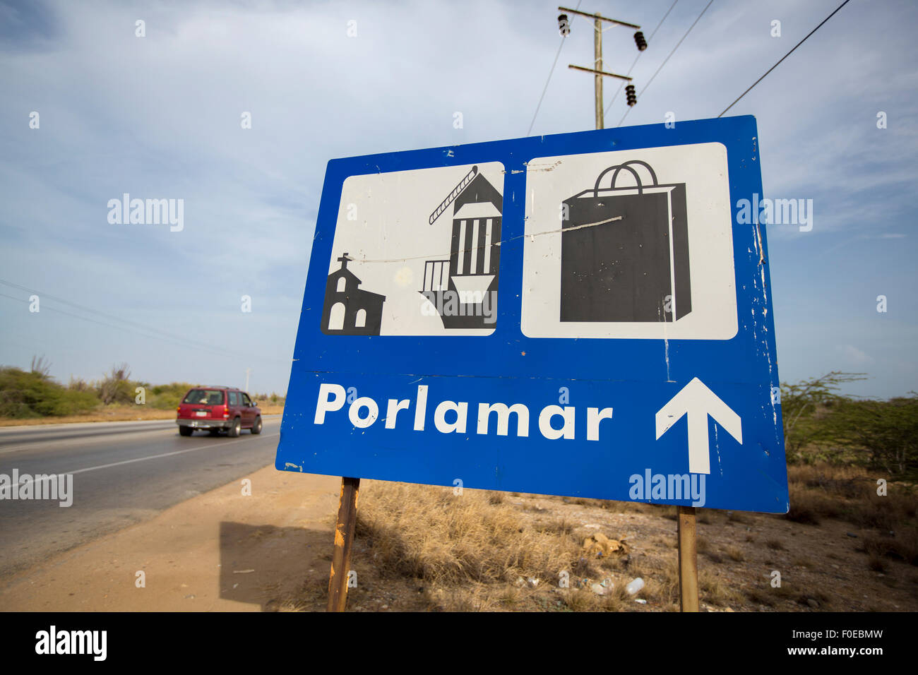 Panneau Bleu donnant la direction de la route Porlomar avec voiture rouge floue passent dans le fond. L'île de Margarita au Venezuela. Banque D'Images