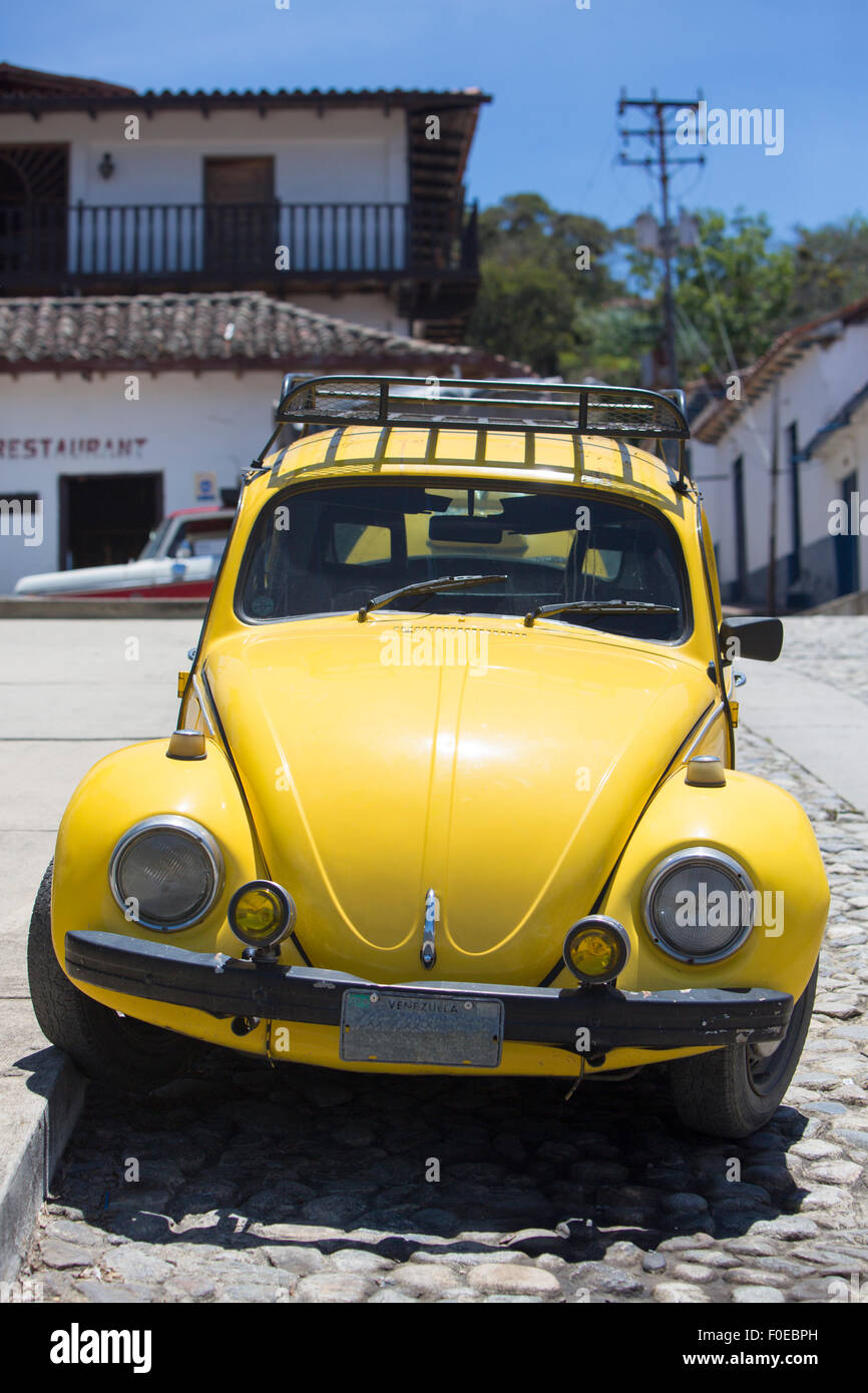 Horloge jaune coccinelle Volkswagen stationné dans la rue d'une ville coloniale dans l'état de Mérida, Venezuela 2015. Banque D'Images