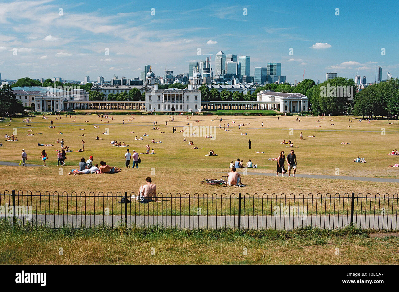 Greenwich Park, sud-est de Londres, Royaume-Uni, en été, avec des baigneurs de soleil et Canary Wharf à distance Banque D'Images
