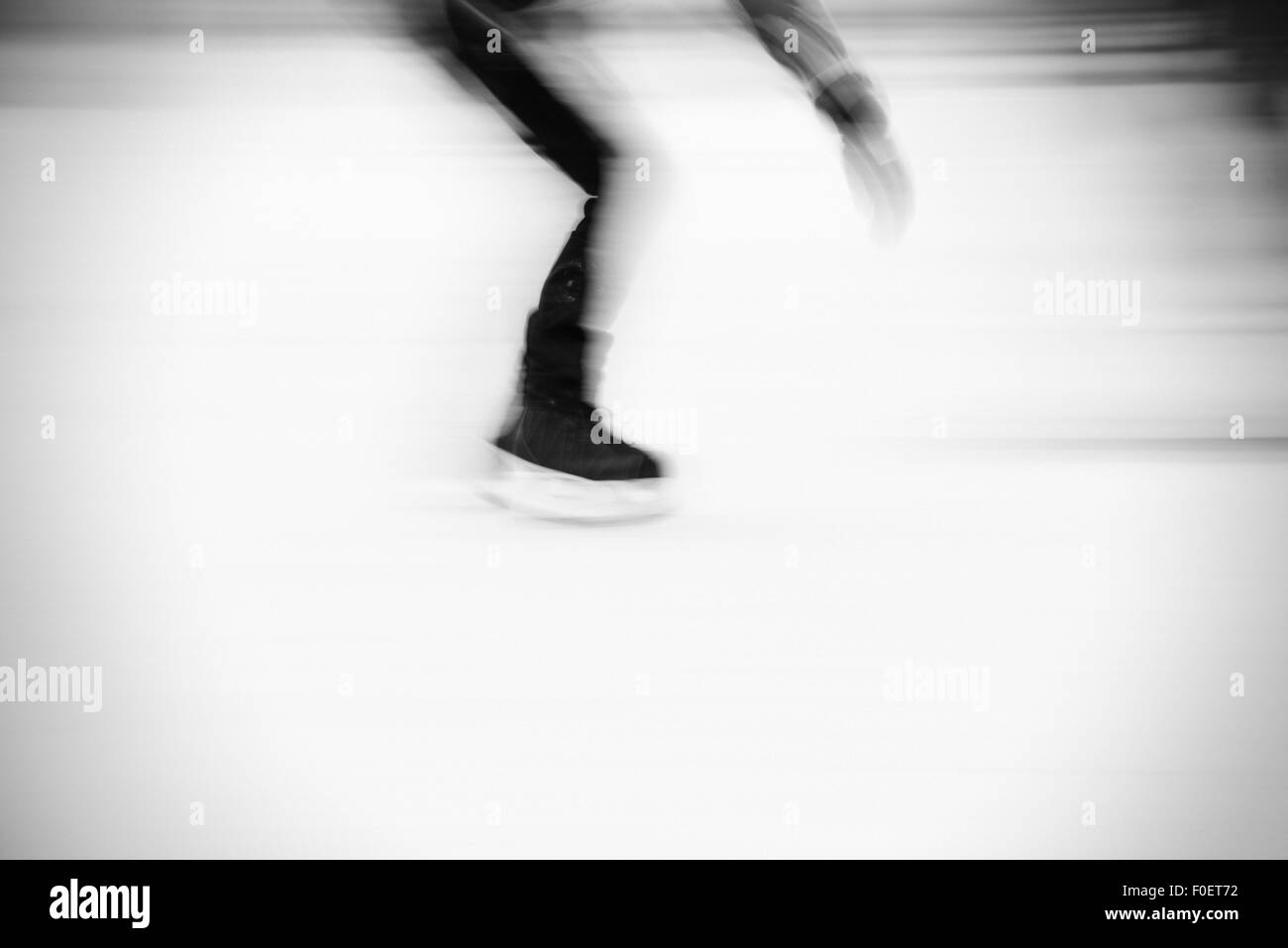 Vue latérale d'homme adulte patinage sur glace en parc. Image floue montrant la vitesse et mouvement. Banque D'Images
