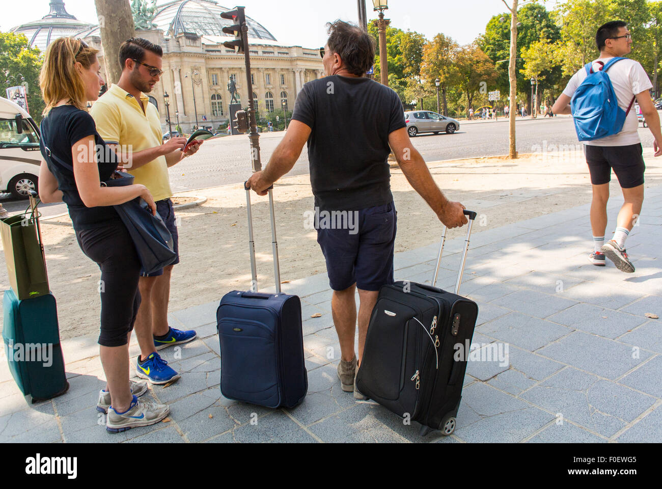 Paris, France, les touristes voyageant avec des bagages sur roulettes sur trottoir sur l'Avenue des Champs Elysées Banque D'Images