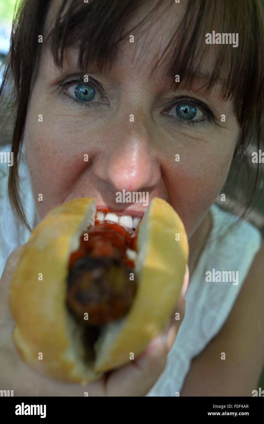 Femme mangeant un hot-dog à la tomate ketchup. Banque D'Images