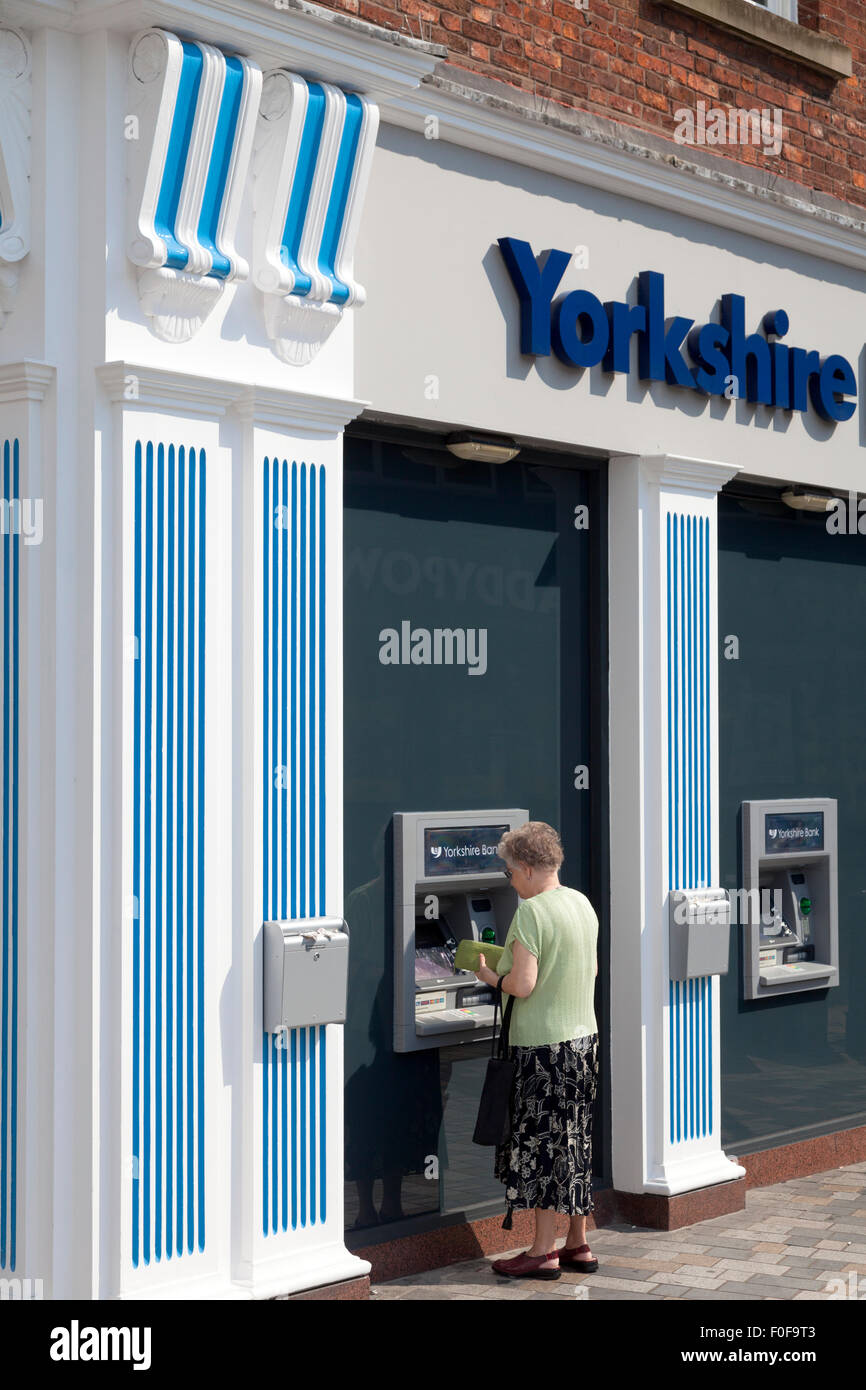 Femme en utilisant un guichet automatique au Yorkshire Bank, Wakefield, West Yorkshire Banque D'Images