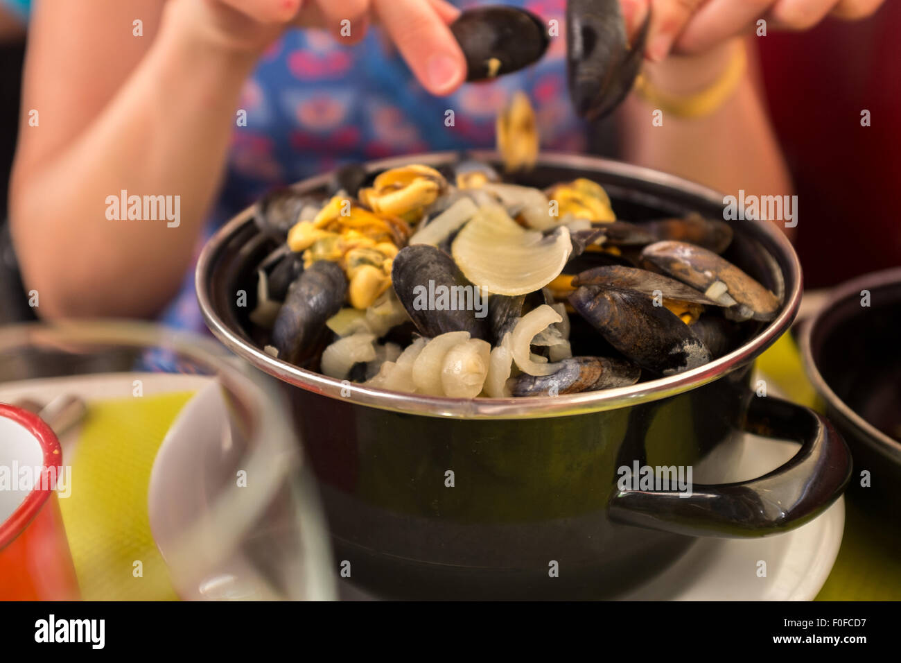 Femme mangeant un bol de moules frites moules avec coquilles vides en vacances en France. Banque D'Images