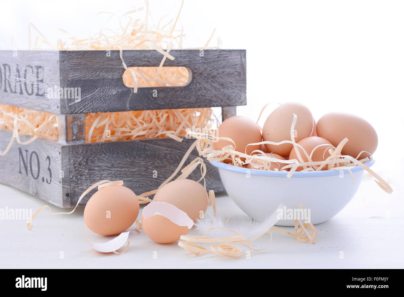 Oeufs frais de la ferme dans un bol avec du bac de rangement sur fond de bois blanc vintage. Banque D'Images