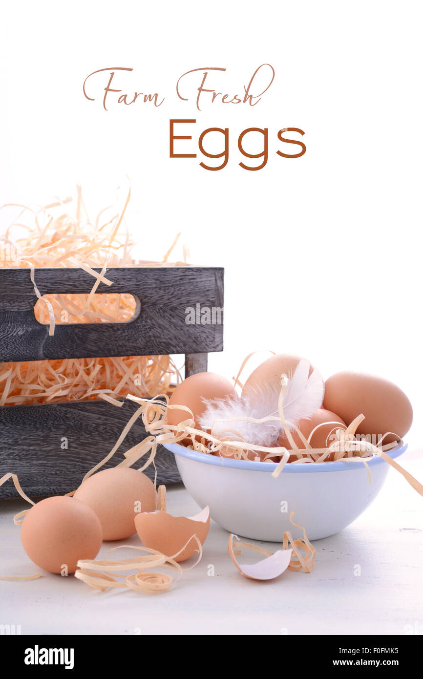 Oeufs frais de la ferme dans un bol avec du bac de rangement sur fond de bois blanc vintage. Banque D'Images