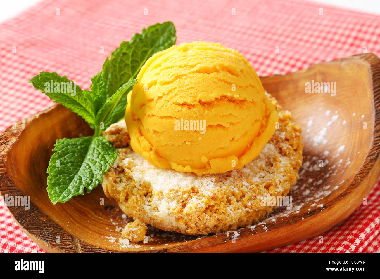 Biscuit aux amandes et boule de glace servi sur un bol en bois d'olivier Banque D'Images