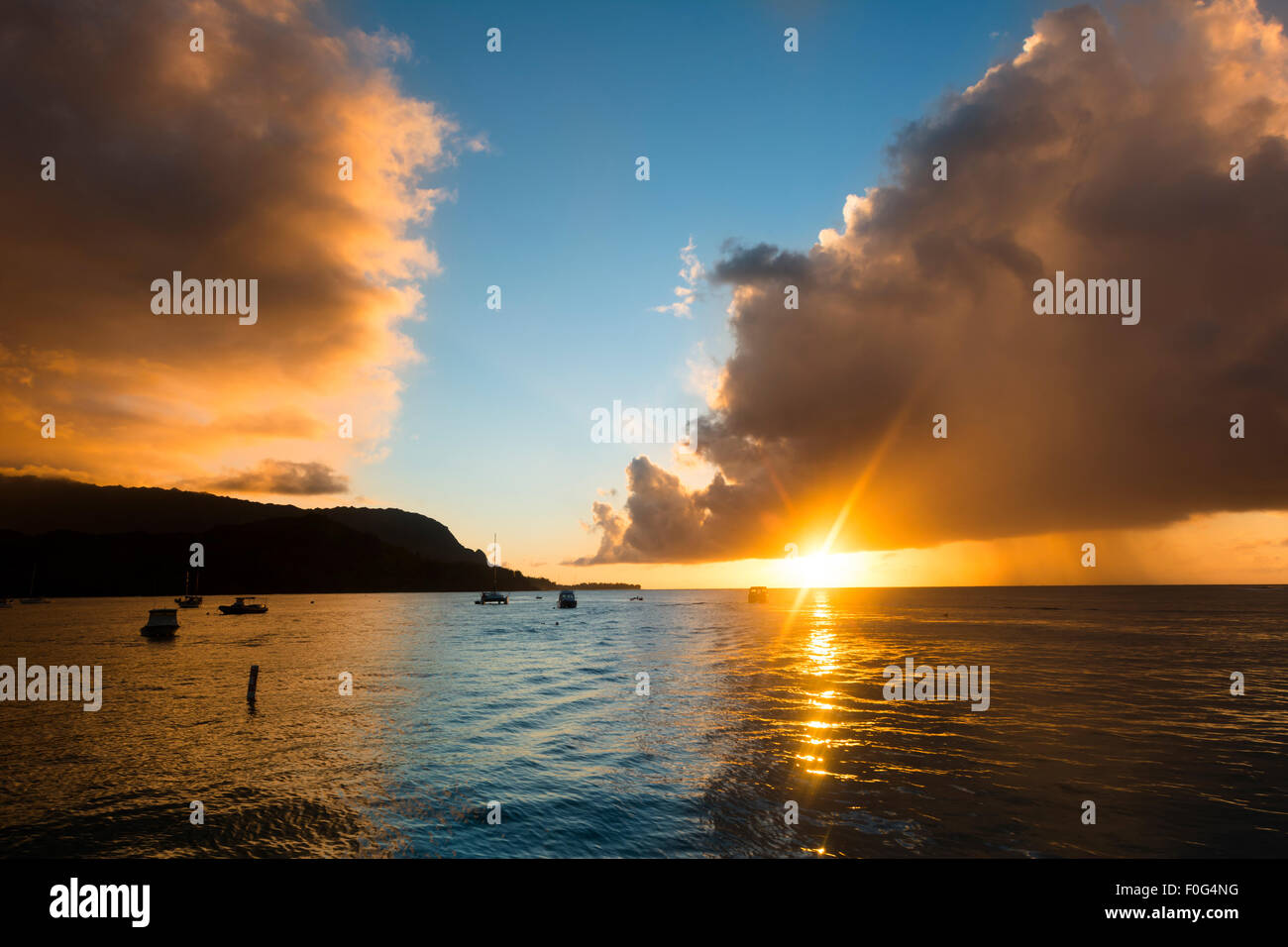 Un coucher de soleil Hawaiien, après une tempête montre les nuages sombres plus persistants le calme Baie d'Hanalei. Banque D'Images