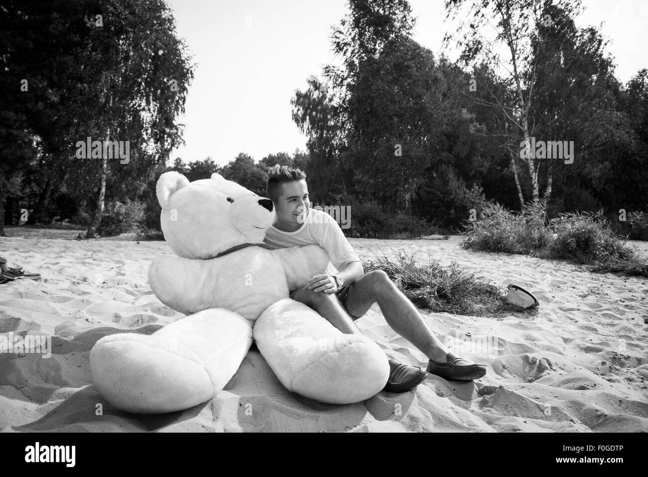 Beau jeune homme est de jouer avec son énorme ours en peluche. Banque D'Images