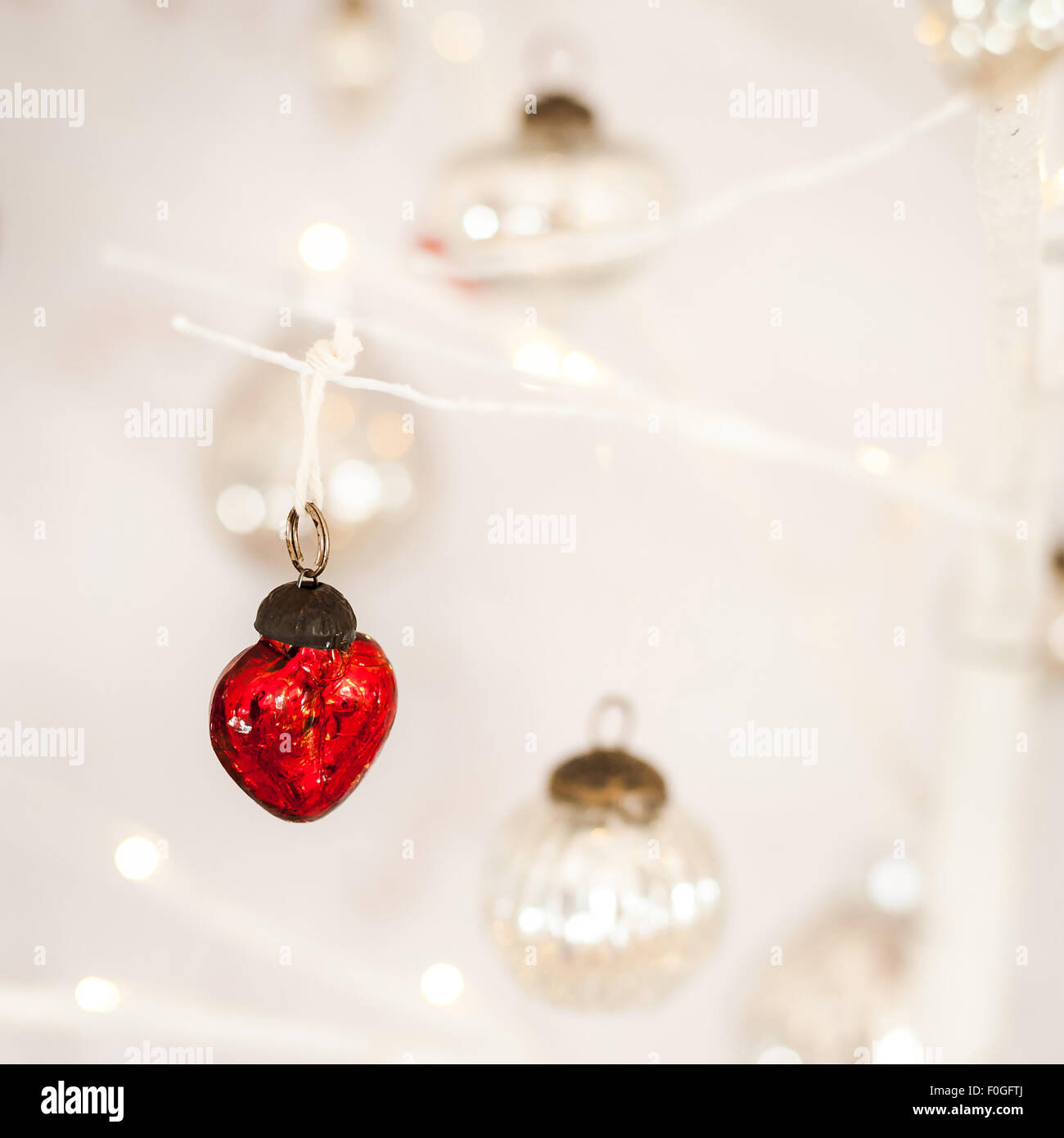 Libre de verre rouge en forme de coeur en argent et boules de Noël dans l'arrière-plan flou Banque D'Images