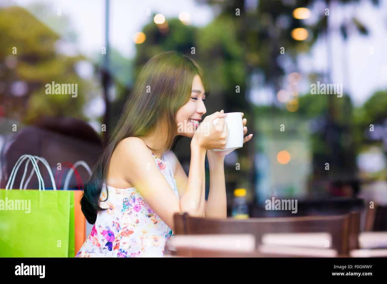 Smiling young woman drinking coffee in cafe shop Banque D'Images