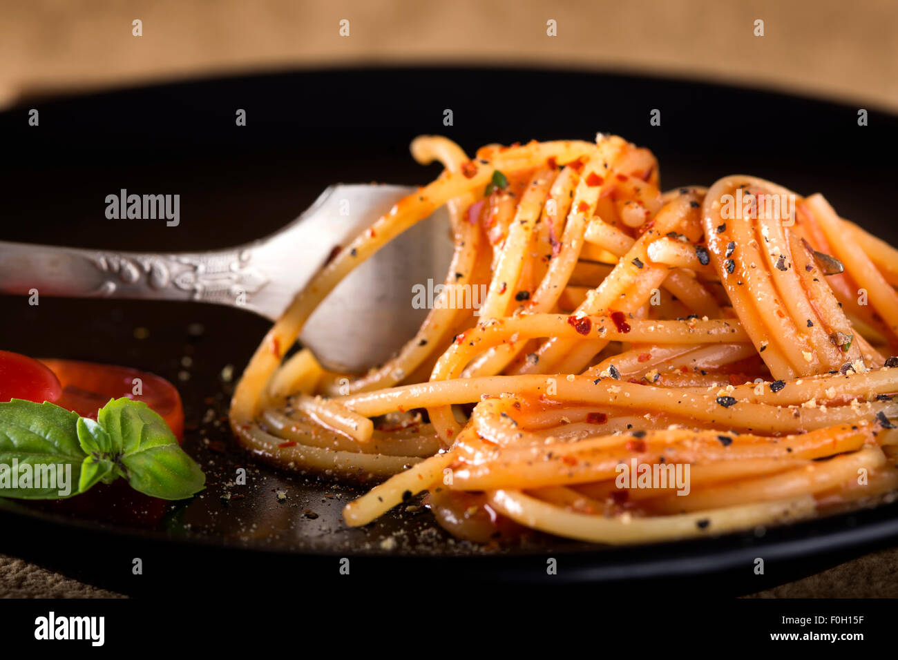 Spaghetti italien de la fourchette sur une assiette avec la sauce tomate et basilic Banque D'Images