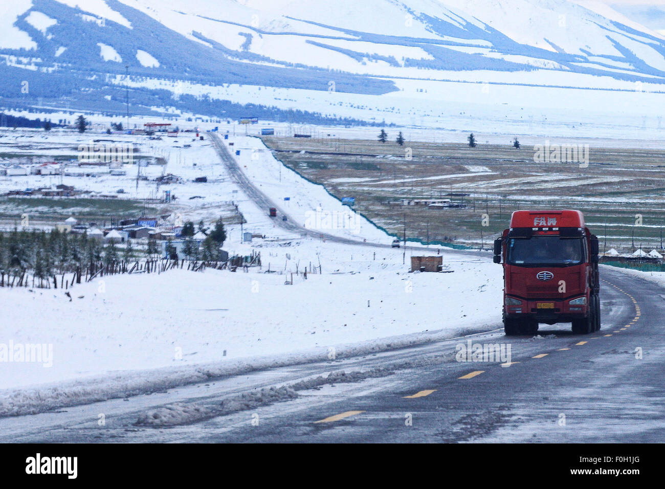 Hami. Août 16, 2015. Une voiture roule sur une route couverte de neige dans la région de Hami de la région autonome du Xinjiang Uygur, 16 août 2015. La région montagneuse de la région de Tianshan a vu une chute de neige précoce le dimanche. Credit : Polat/Xinhua/Alamy Live News Banque D'Images