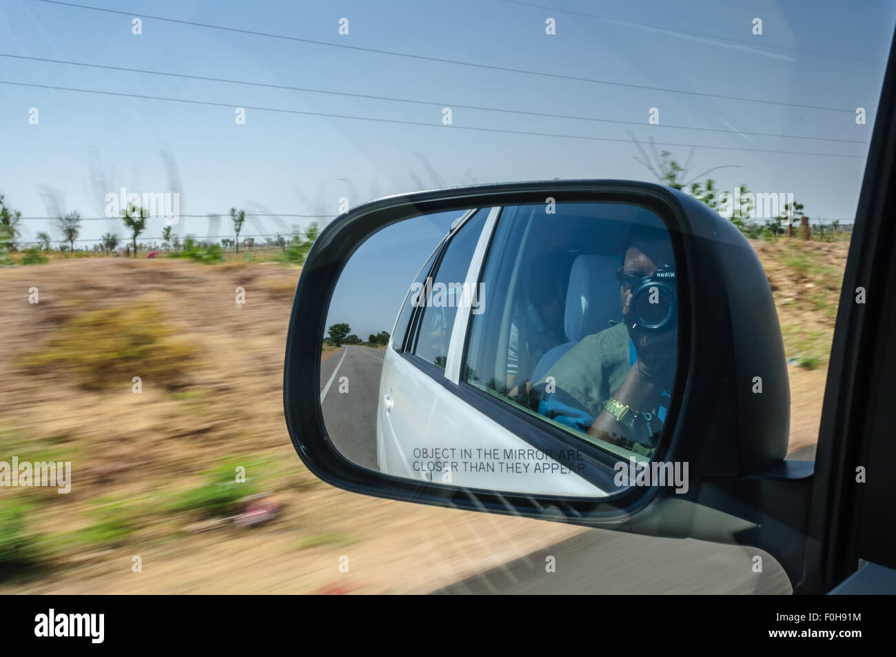 Vue à travers le rétroviseur d'une voiture sur l'autoroute à grande vitesse dans le désert environnant avec motion blurred copy space Banque D'Images