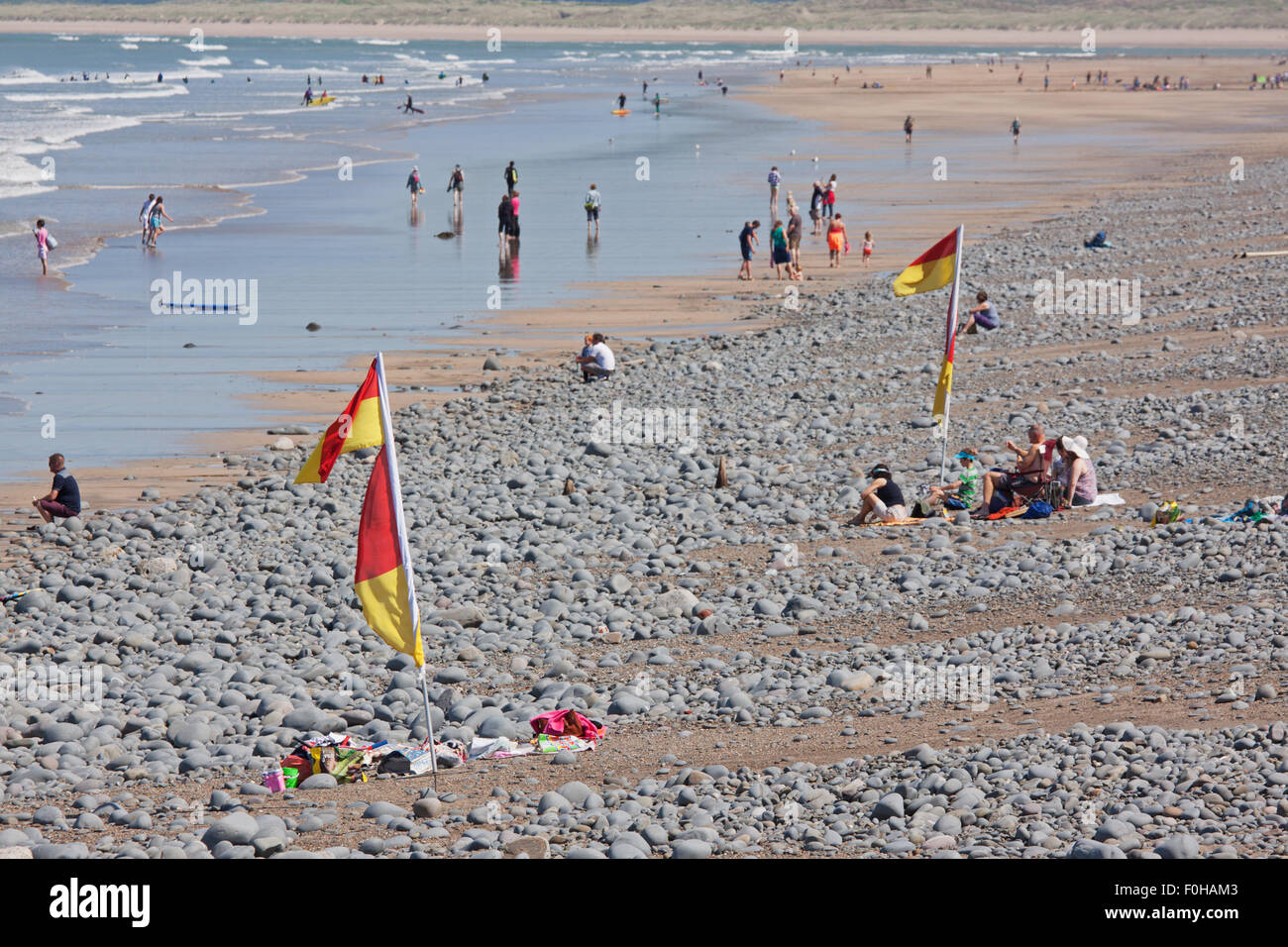 Les vacanciers appréciant le début de l'été sur une plage de North Devon. Les drapeaux jaunes et rouges indiquent les zones de baignade en toute sécurité Banque D'Images