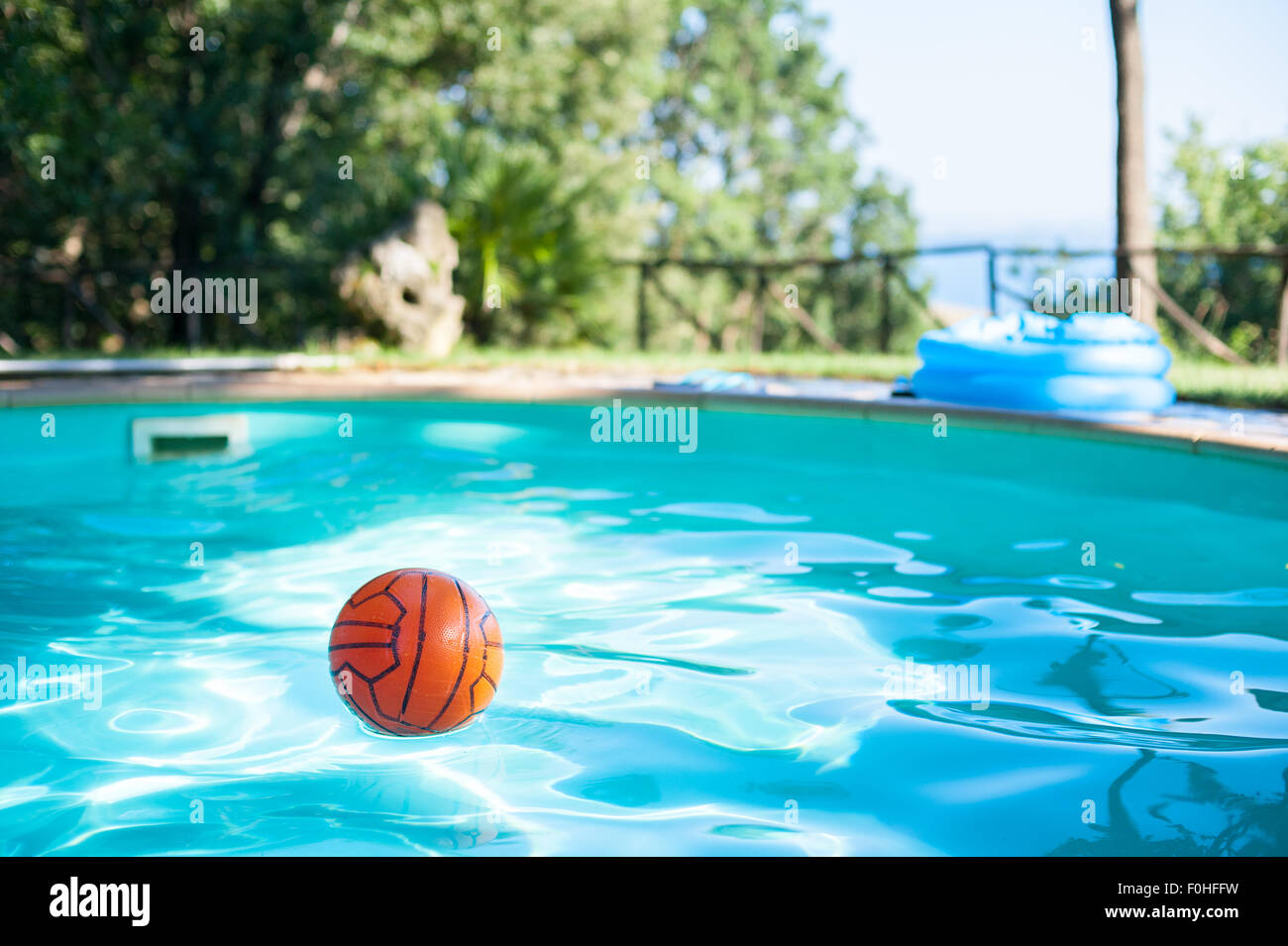 Boule rouge dans une piscine vide en vert jardin selective focus Banque D'Images