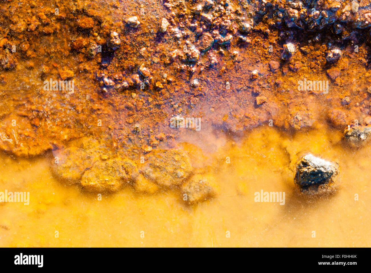 La pollution. Flaque d'eau gelée jaune, avec des polluants et de minéraux, s'infiltre à travers le sol orange dans l'eau, se décolorer les deux. Banque D'Images