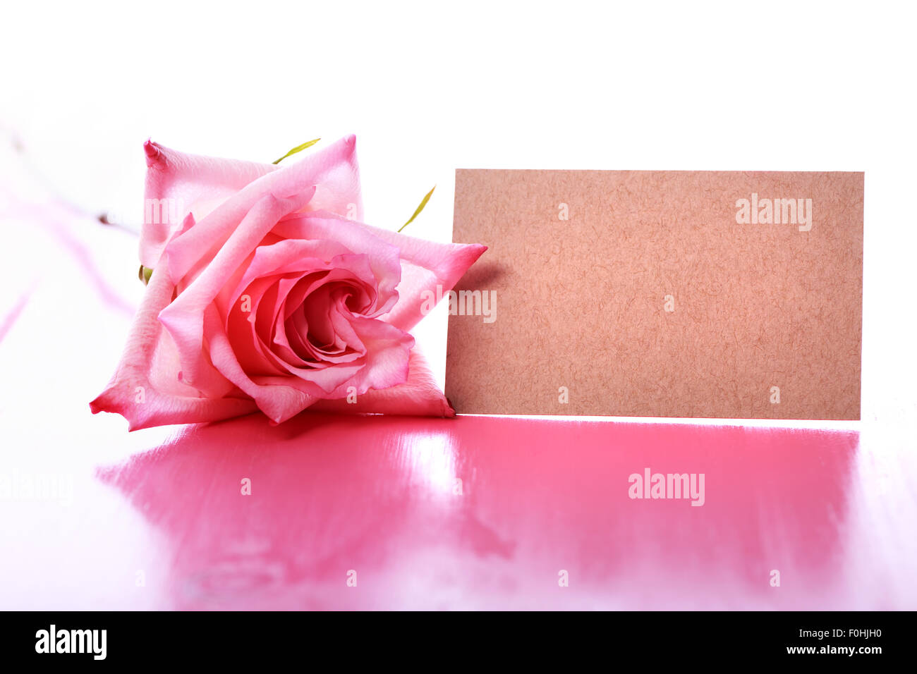 Rose rose avec un message vierge carte sur table en bois de rose Banque D'Images