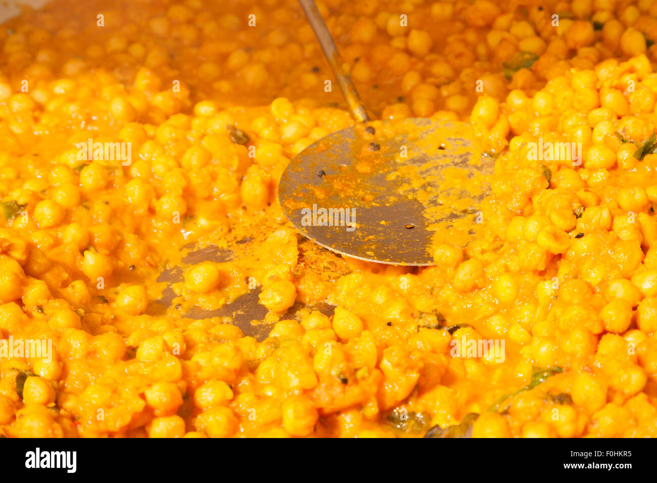 La photo en gros plan d'un grand plat de chana daal - ragoût de pois chiches spicey avec une louche en remuant. Banque D'Images
