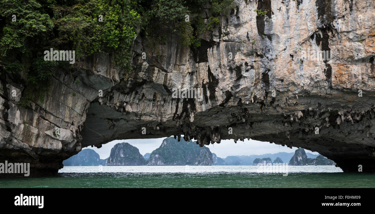 Piliers karst calcaire encadrée par pierre naturelle arch dans la baie de Halong Vietnam Banque D'Images