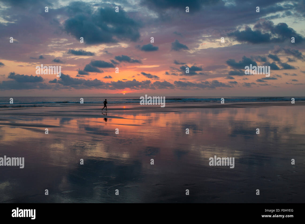 Vue du coucher de soleil sur la plage de Matapalo grâce à silhouette de l'homme faisant son jogging, le Costa Rica. Banque D'Images