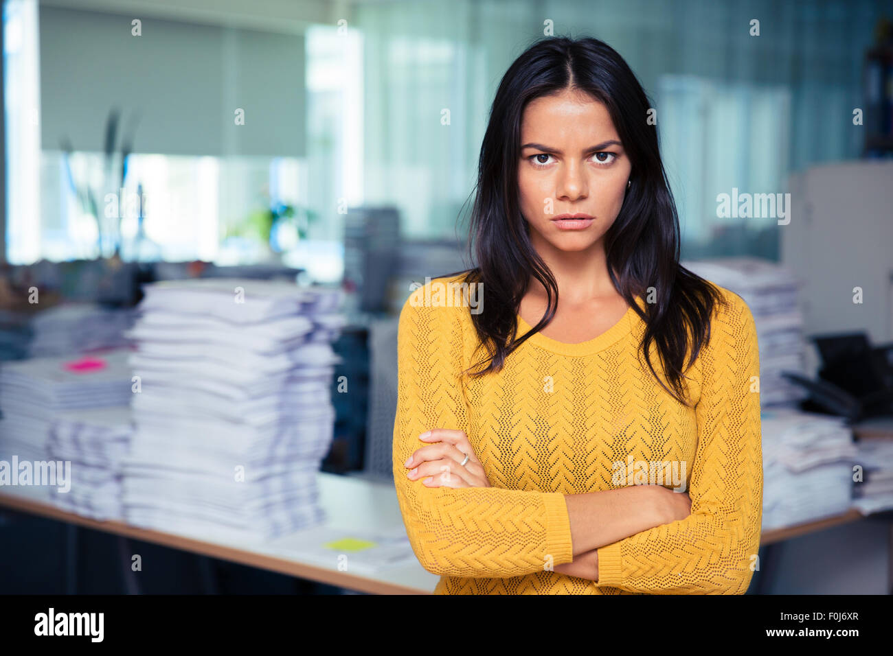 Portrait of angry businesswoman standing with arms folded in office Banque D'Images