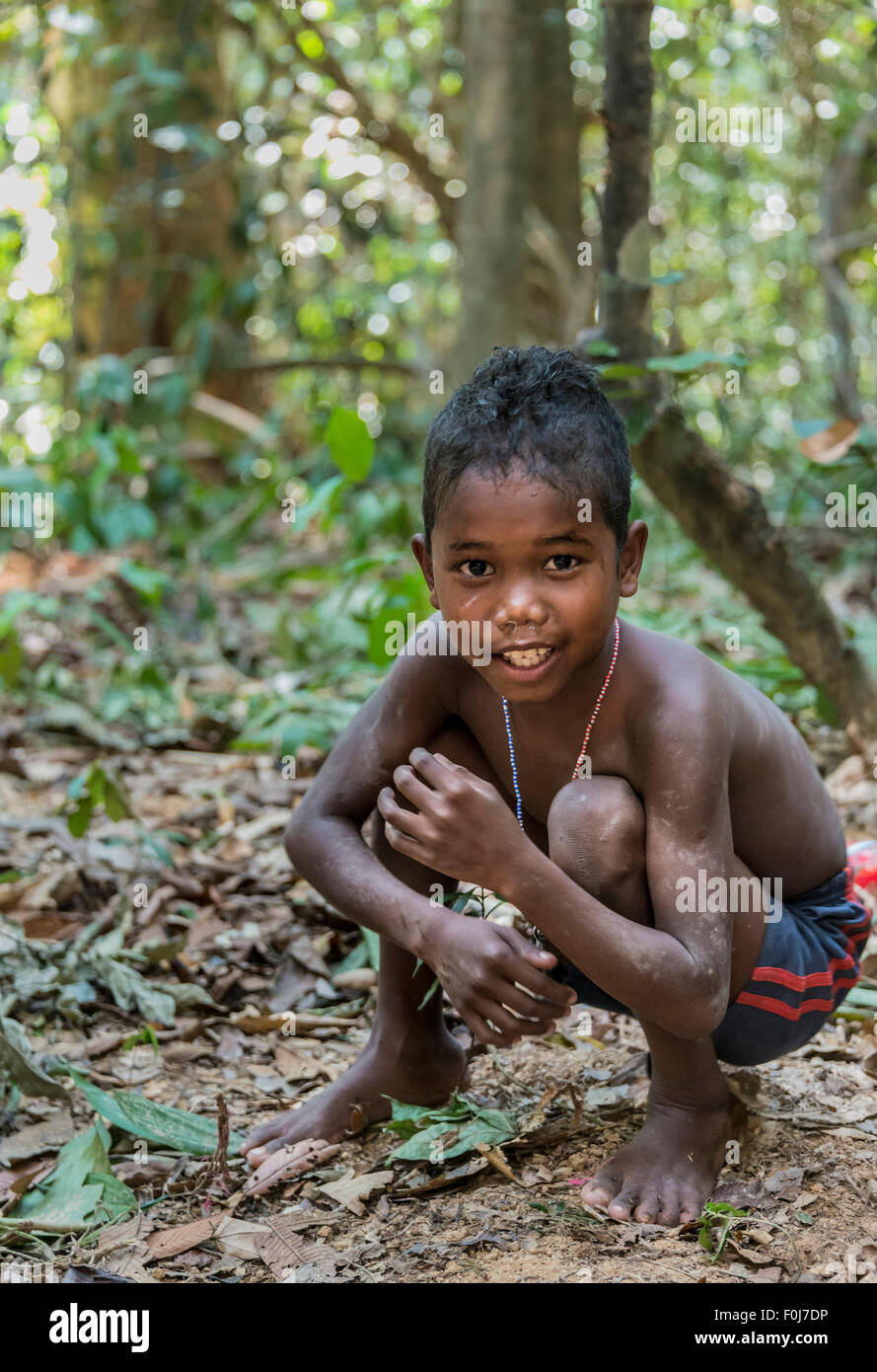 Petit garçon de la tribu Orang Asil grimaçantes, accroupis sur le sol dans la jungle, les autochtones, les communautés autochtones Volk Banque D'Images