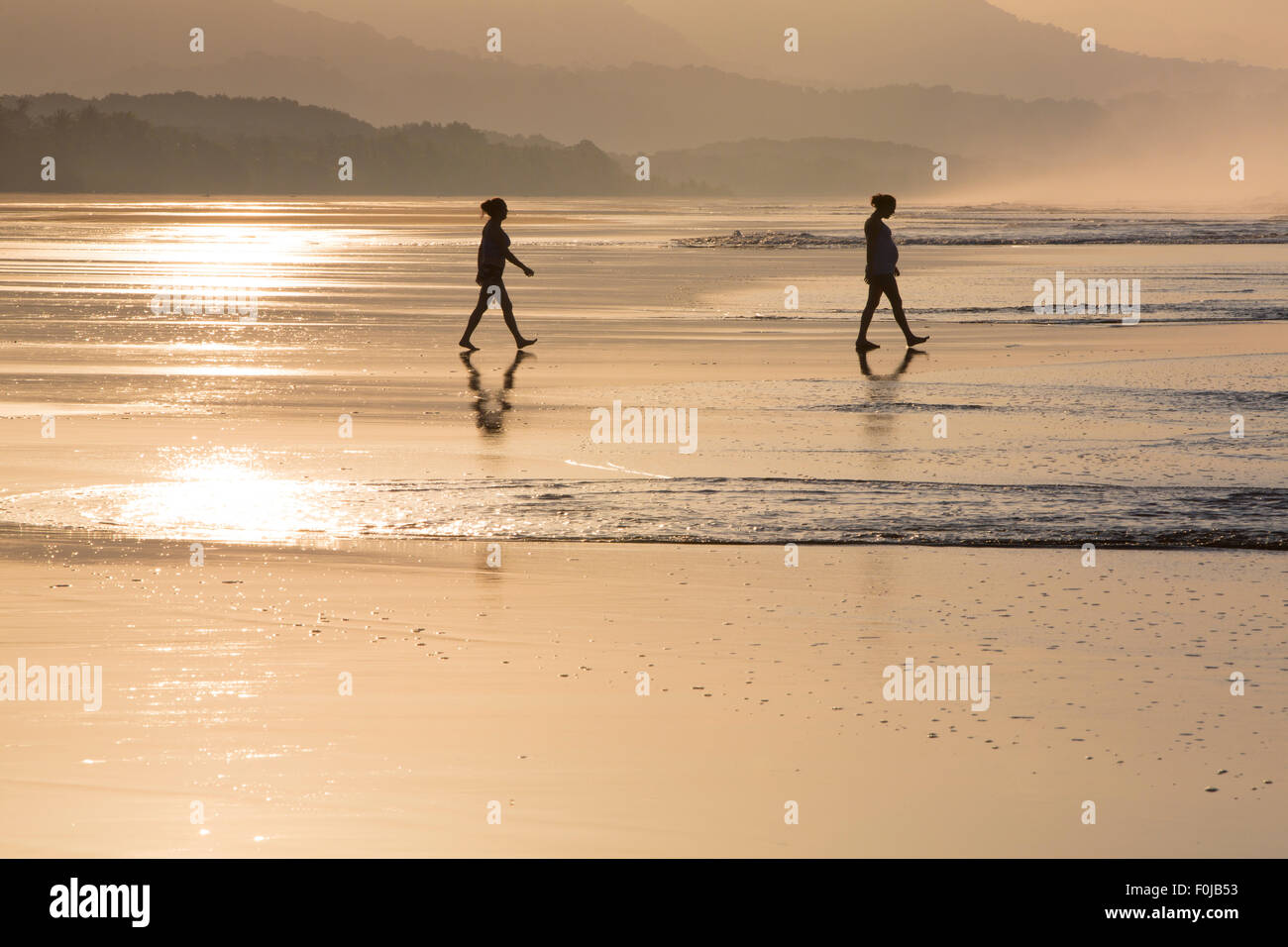 Silhouette de deux personnes marchant sur la plage avec la lumière du matin tôt le matin dans la région de Matapalo, Costa Rica 2013 Banque D'Images