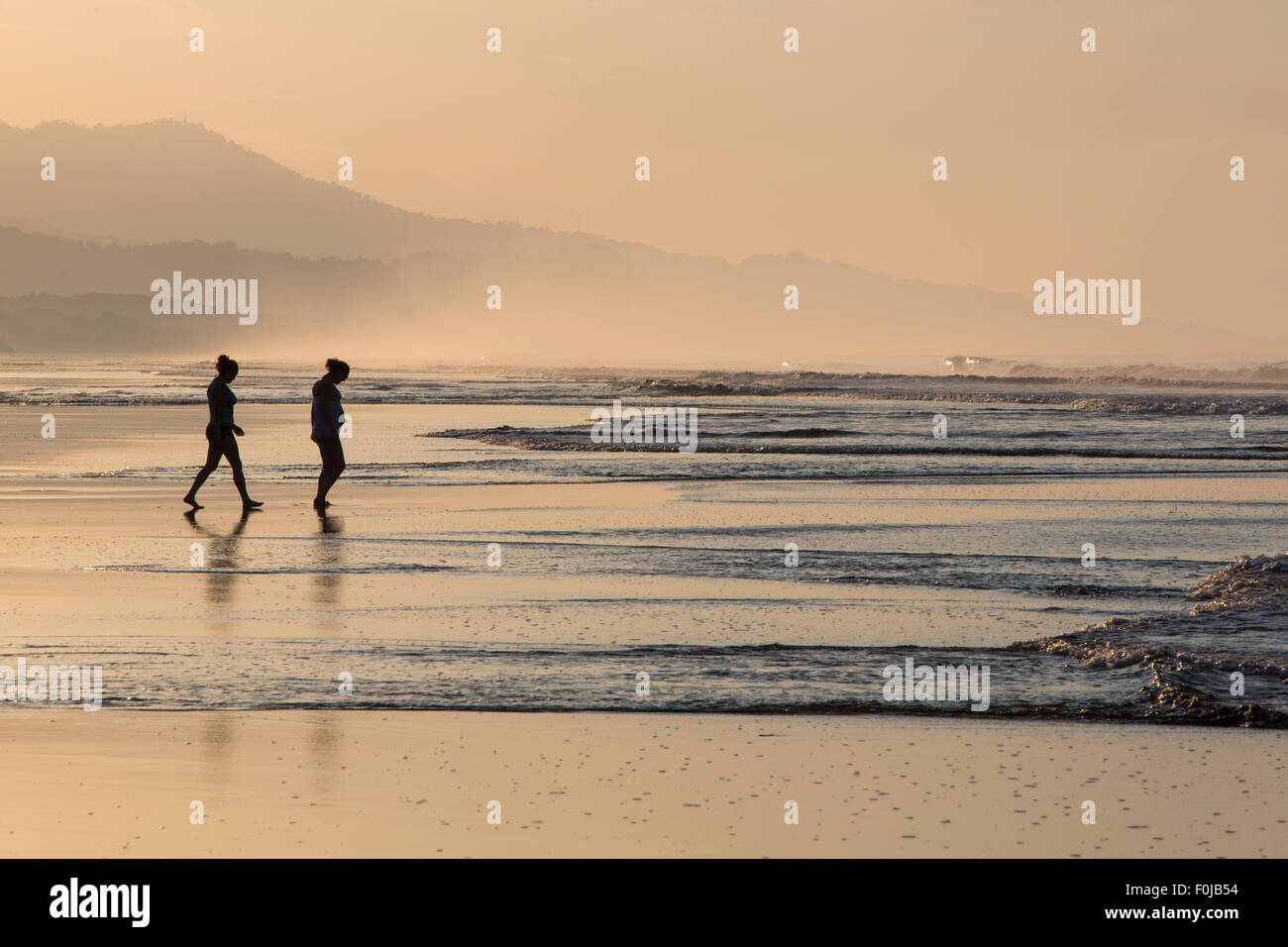 Silhouette de deux personnes marchant sur la plage avec la lumière du matin tôt le matin dans la région de Matapalo, Costa Rica 2013 Banque D'Images