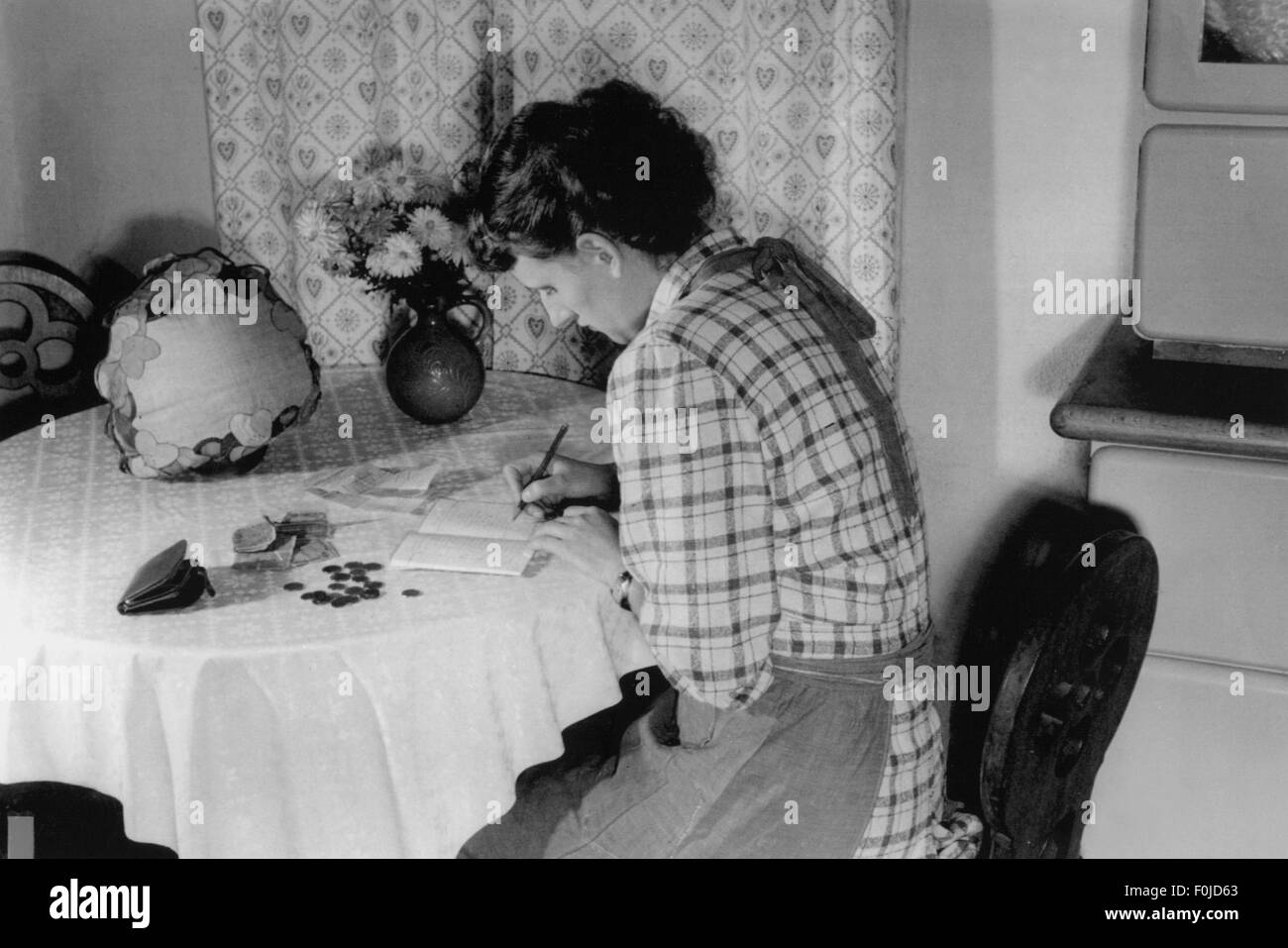 Ménage, femme assise à la table de cuisine écrivant dans le livre de ménage, années 1940, droits supplémentaires-Clearences-non disponible Banque D'Images