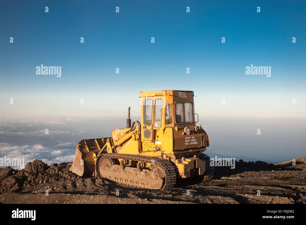 Ciel bleu avec tracteur jaune en haut de la montagne Etna avec vue sur les nuages et la vallée Banque D'Images
