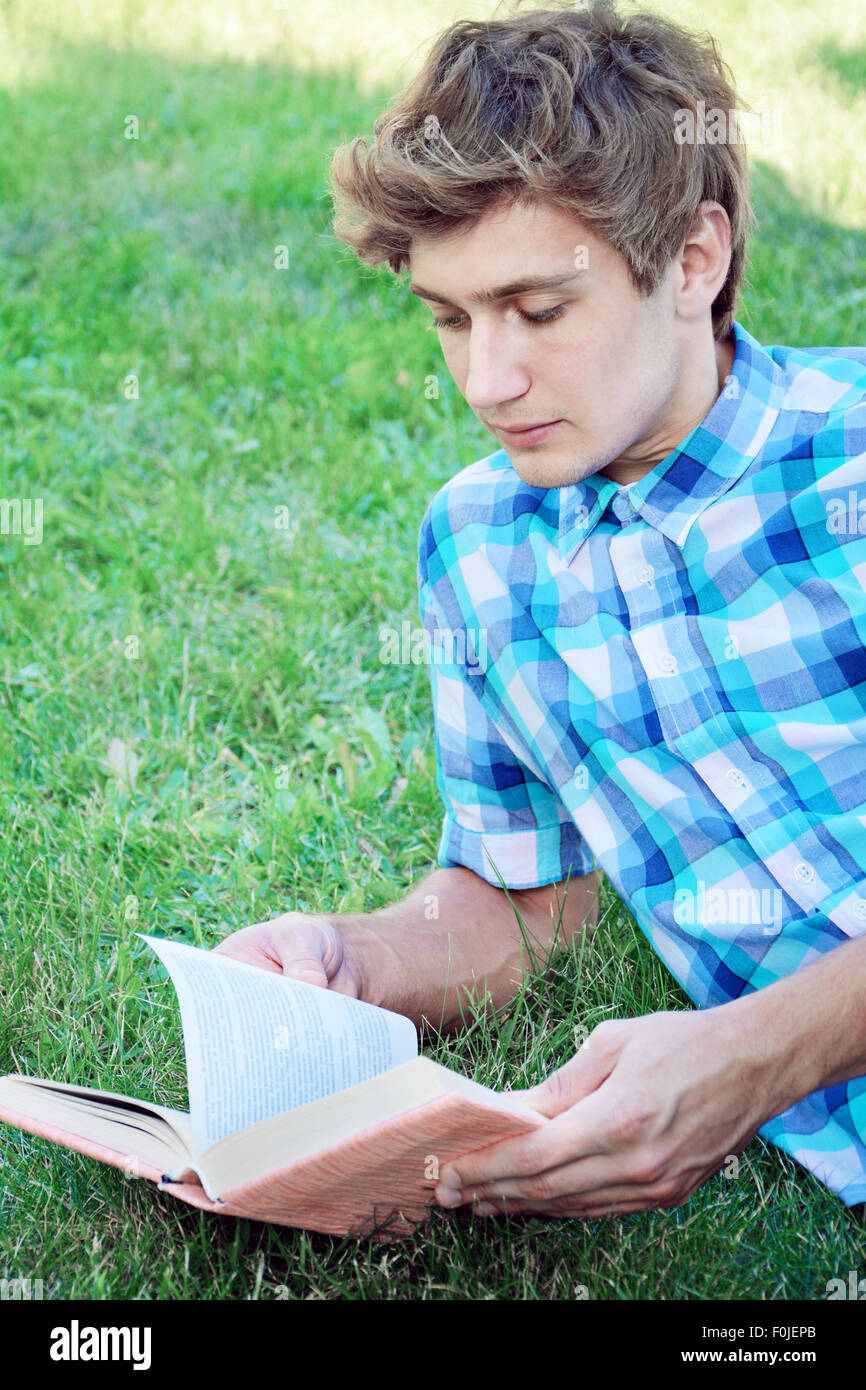 Jeune homme est la lecture d'un livre portant sur l'herbe Banque D'Images