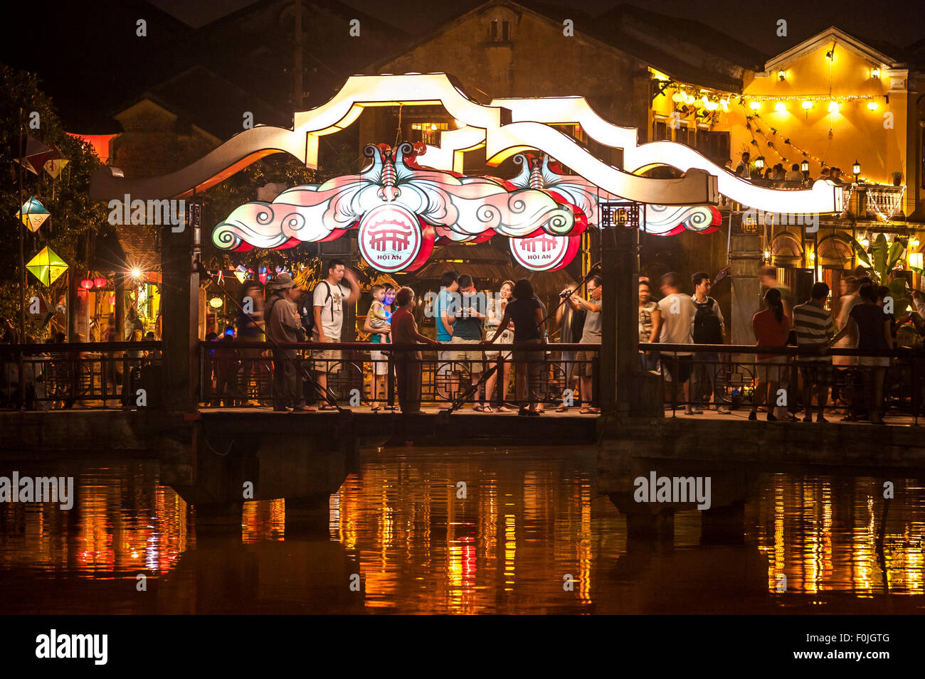 Le tourisme au Vietnam, les touristes foule illuminée le pont enjambant la rivière Thu Bon à Hoi An, Vietnam central. Banque D'Images