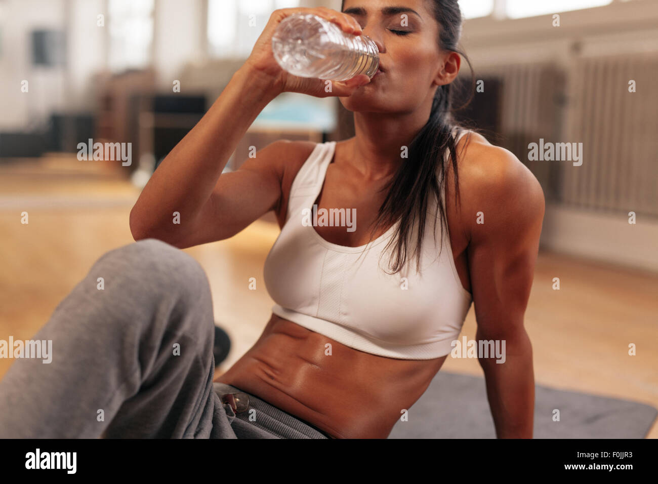 Femme de remise en forme de la bouteille de l'eau potable. La jeune femme à gym prendre une pause pour l'entraînement. Banque D'Images