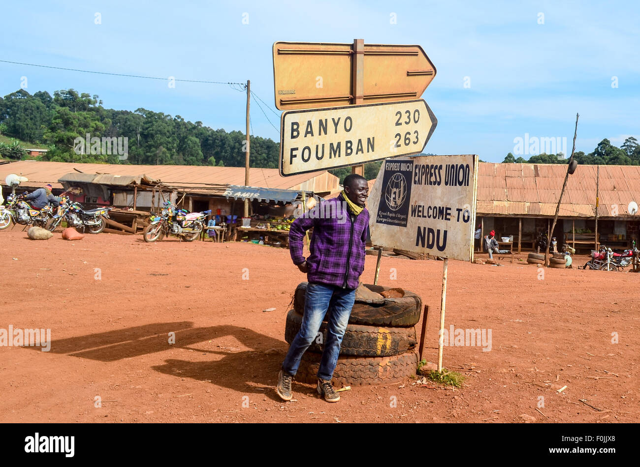 Homme debout en dessous d'un panneau routier au Cameroun Banque D'Images