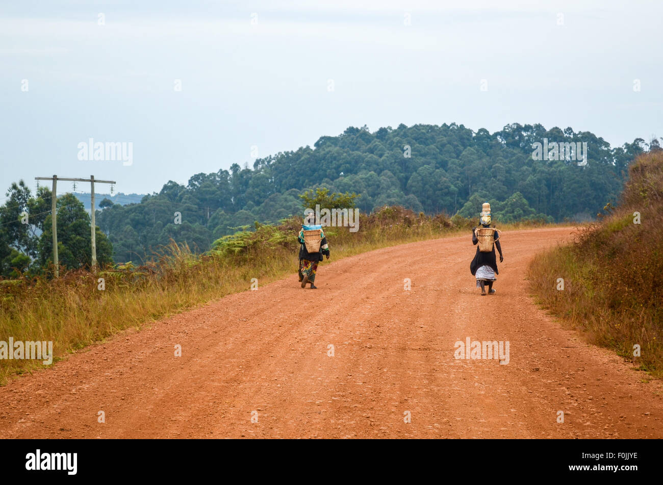 Des femmes de la marche sur une terre rouge route de terre en milieu rural en Afrique Banque D'Images