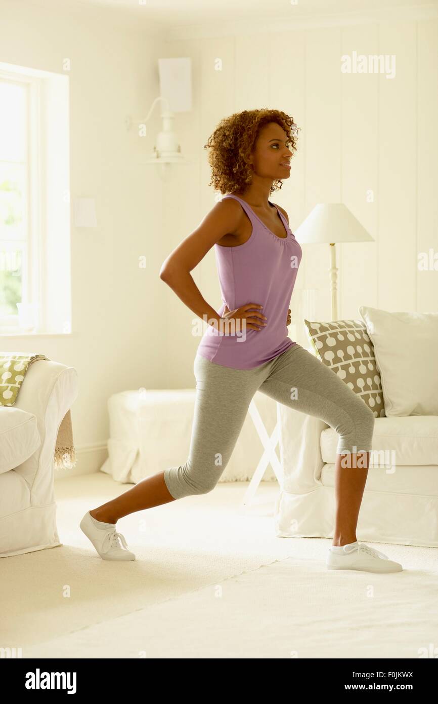 Femme en leggings et débardeur sur une jambe vers l'avant de la scène de l'exercice, side view Banque D'Images