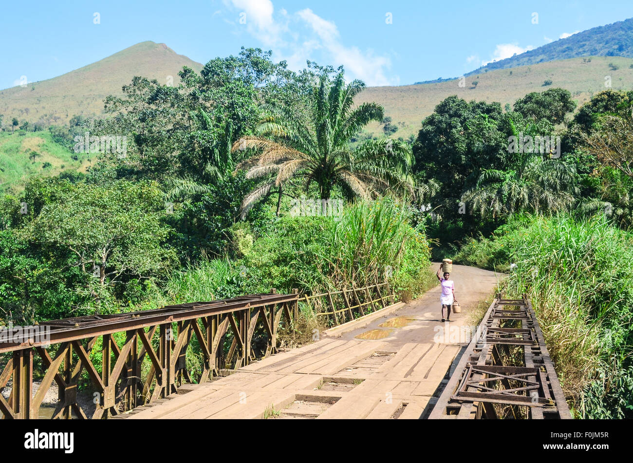 Jeune fille portant un seau sur la tête au Cameroun la marche sur un vieux pont colonial Banque D'Images