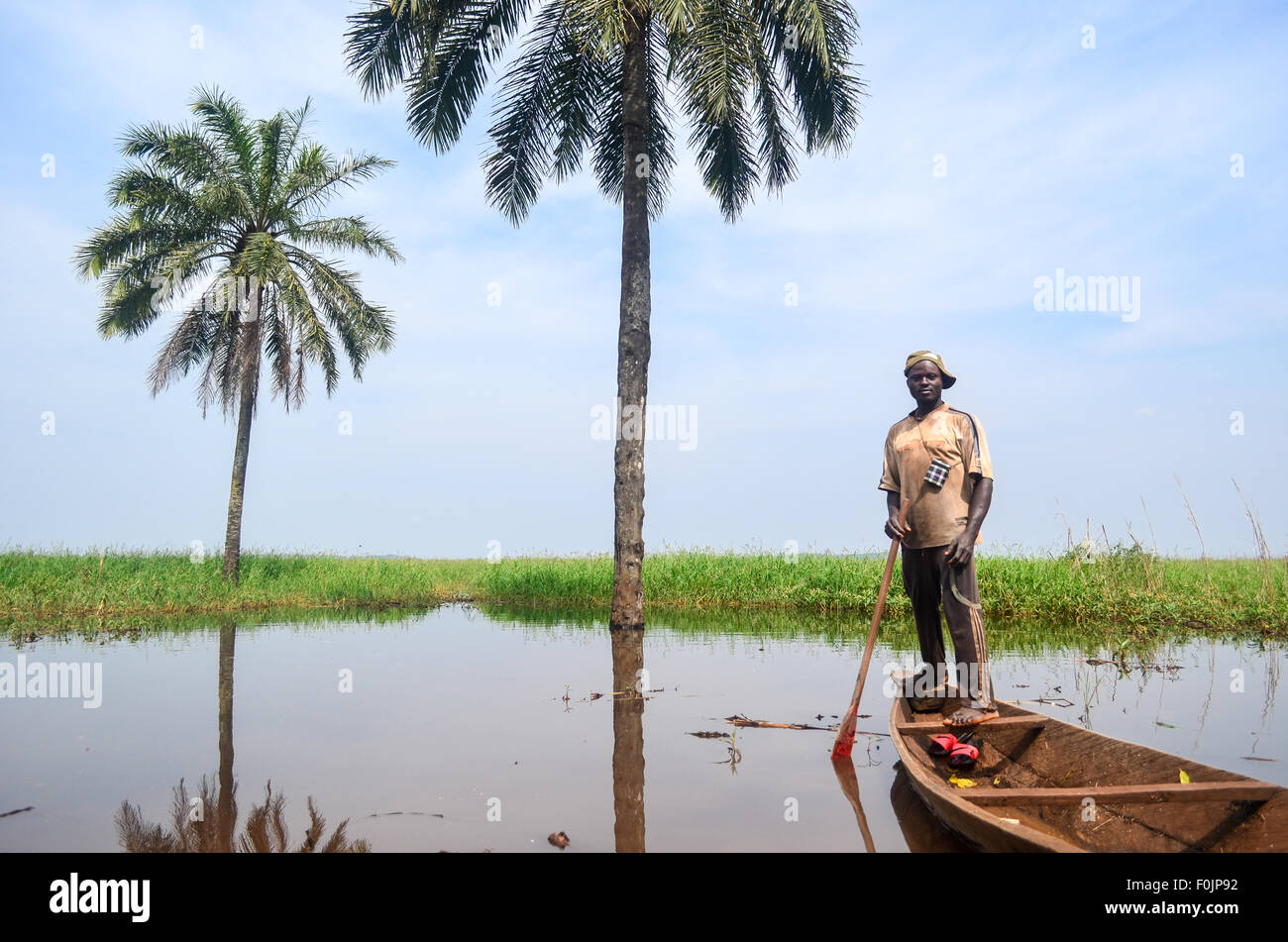 Homme posant avec une pirogue et palmier au Cameroun Banque D'Images